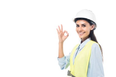 Hardhat ve güvenlik yeleği gülümseyen mühendis beyaz üzerinde izole iyi işareti gösteren