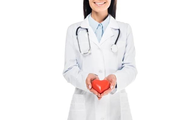 プラスチックの心臓の白で隔離を保持している白衣の医者の部分的なビュー — ストック写真