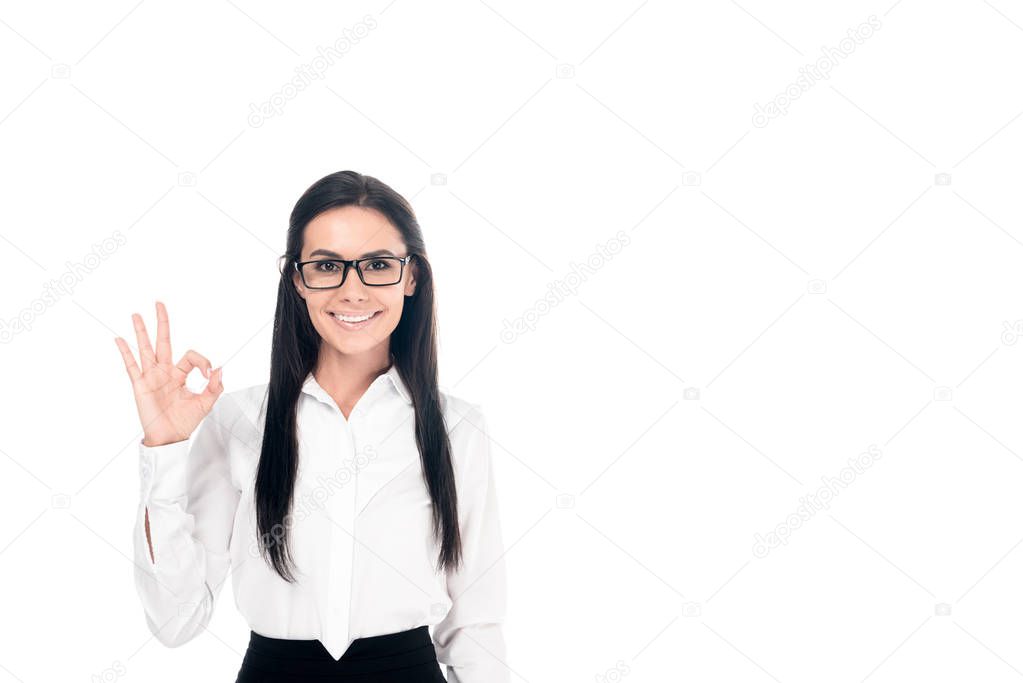 Smiling businesswoman in glasses showing okay sign isolated on white