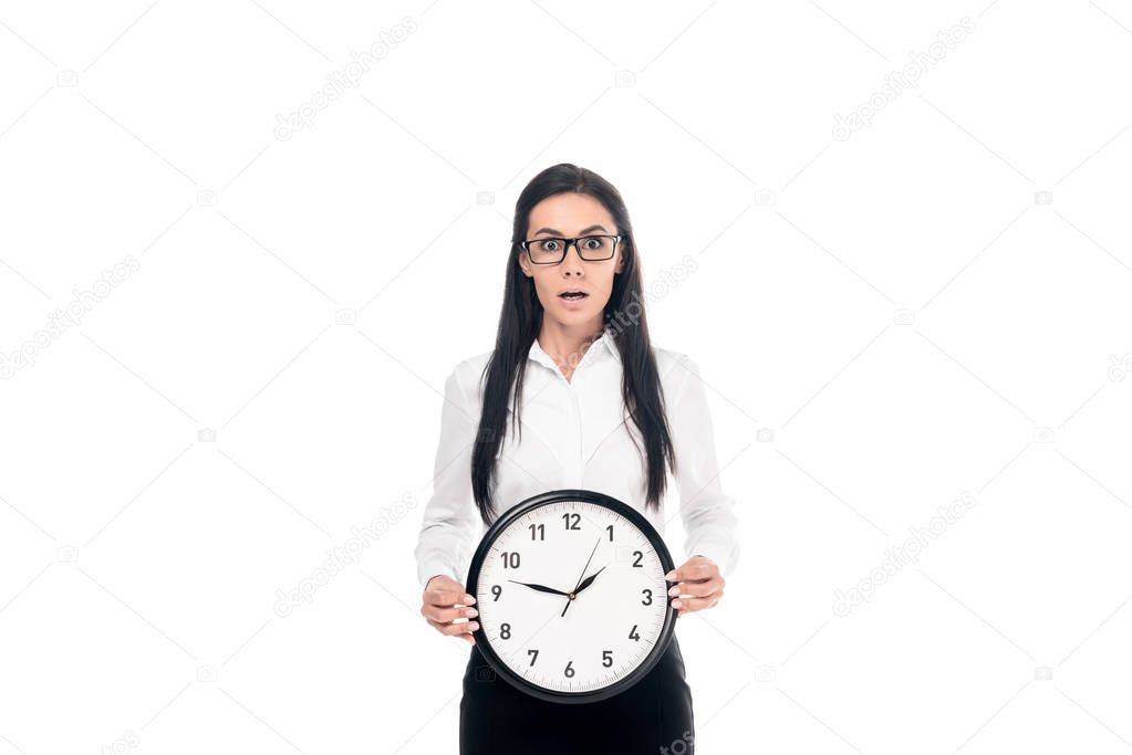 Shocked brunette businesswoman in shirt holding clock isolated on white