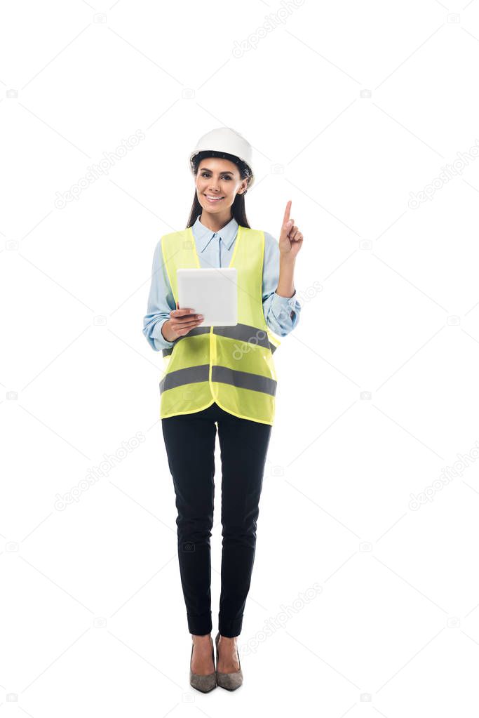 Full length view of engineer in safety vest using digital tablet and pointing with finger isolated on white