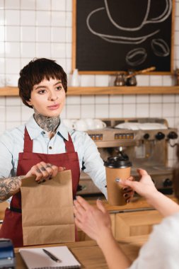 çok gülümseyen barista kağıt torba ve tek kullanımlık Kupası müşteriye verilmesi