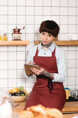 not defterinde yazılı ve kameraya bakarak önlük güzel barista seçici odak
