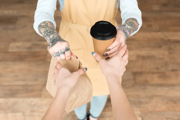 Vista Cortada Garçonete Tatuado Dando Saco Papel Copo Descartável Para — Fotografia de Stock