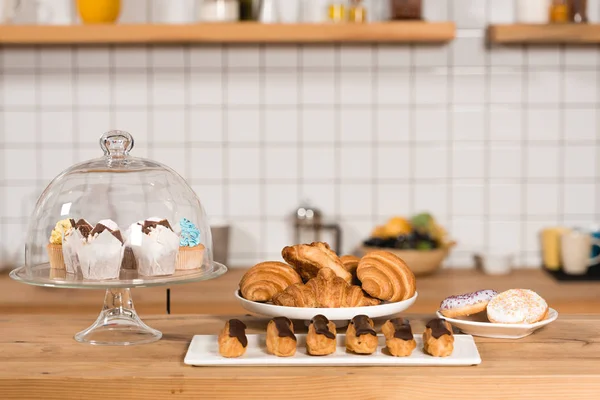 wooden bar counter with croissants, cakes, eclairs and macaroons in coffee shop