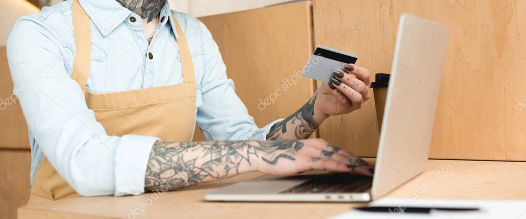 partial view of waitress using laptop and holding credit card
