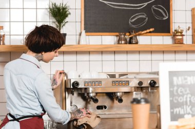 selective focus of barista cleaning espresso machine in coffee shop clipart