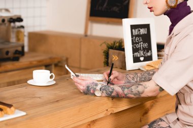 Kısmi smartphone tutarak ve sayacı, otururken not defterinde yazılı işkadını görünümünü