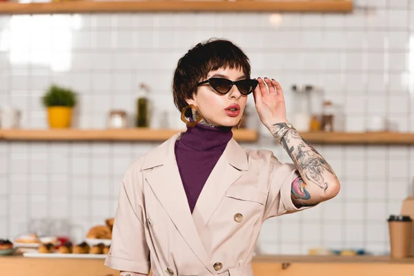 Hermosa Mujer Negocios Tatuada Pie Cafetería Tocando Gafas Sol —  Fotos de Stock