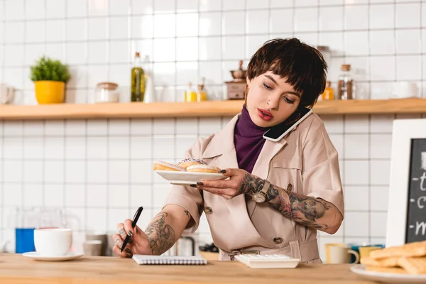 Bonita Mujer Negocios Hablando Teléfono Inteligente Celebración Placa Con Macarrones —  Fotos de Stock