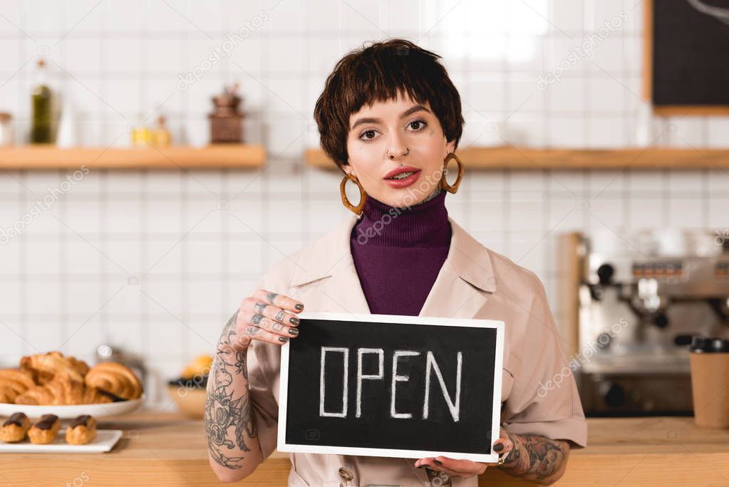 pretty businesswoman holding signboard with open lettering and looking at camera