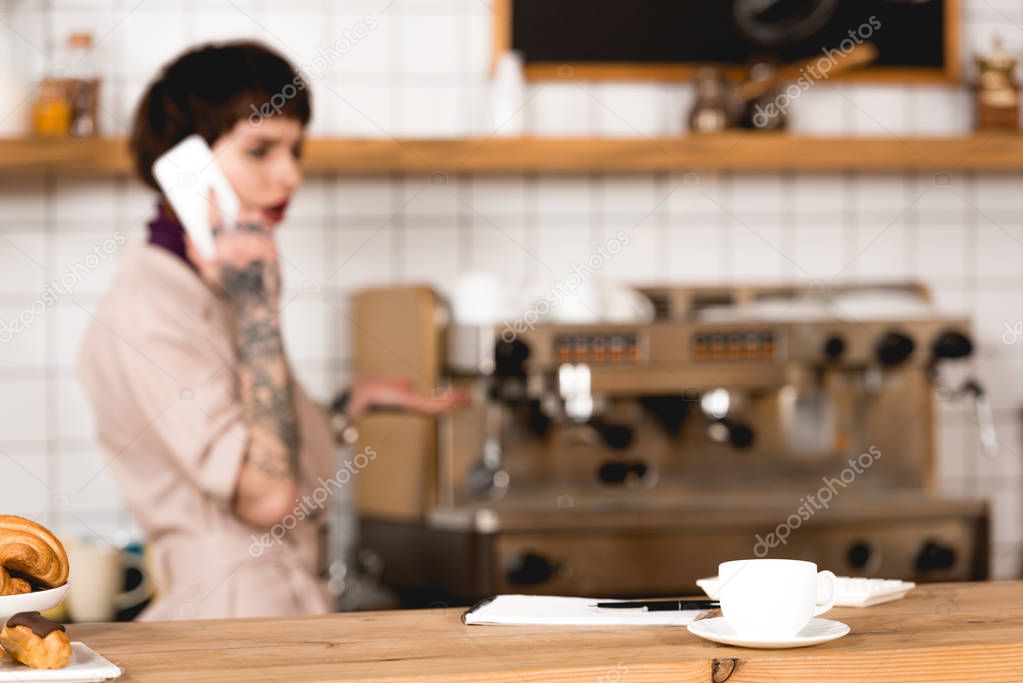 selective focus of businesswoman talking on smartphone in coffee shop