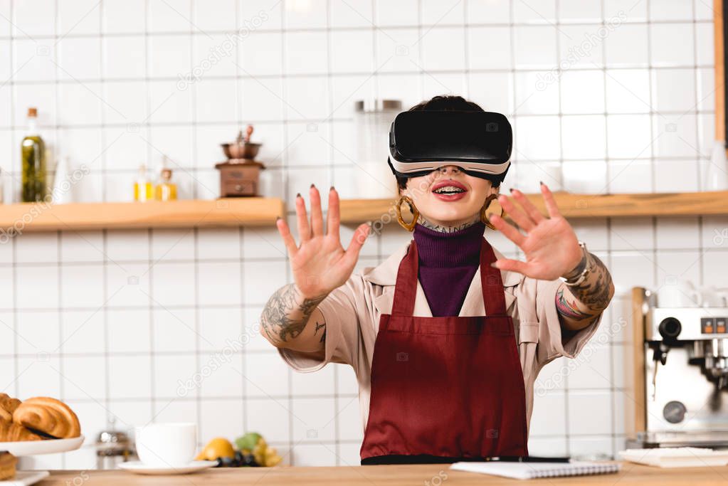 smiling barista in virtual reality headset standing near bar counter in cafteria