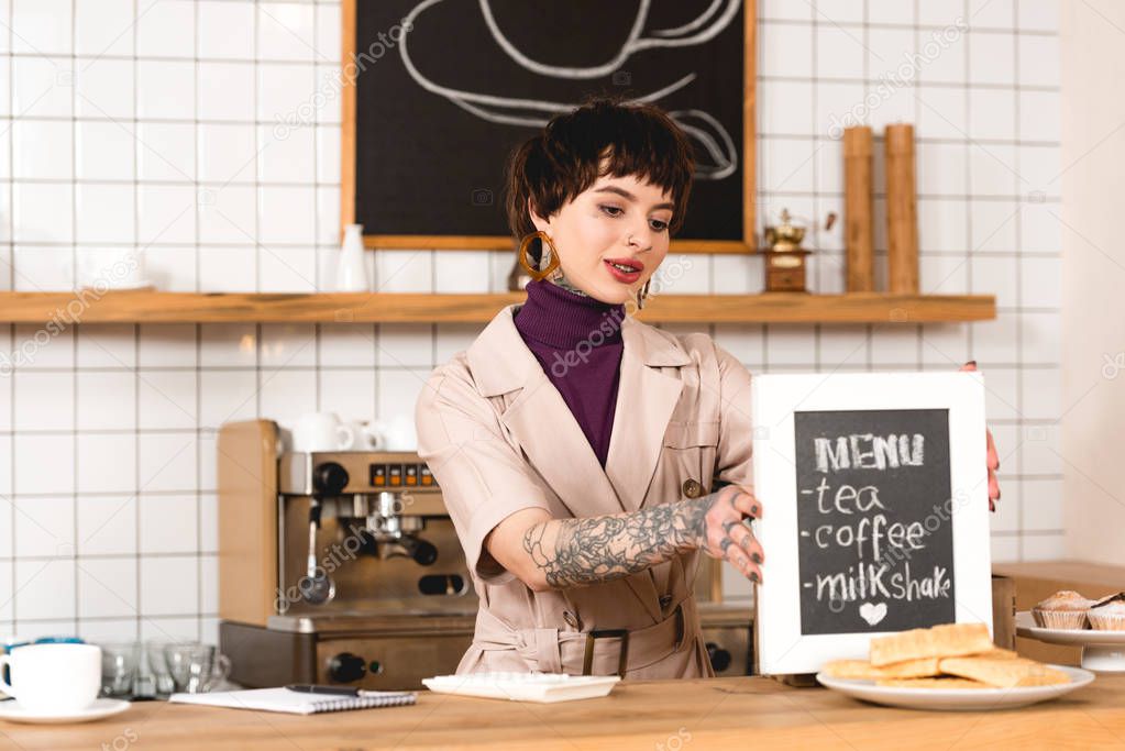 smiling businesswoman placing menu board on bar counter in coffee shop