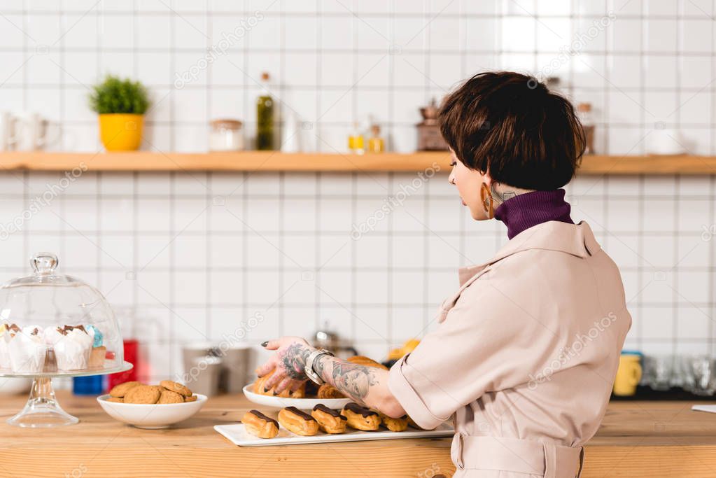 trendy businesswoman placing dishes with pastry on bar counter in cafeteria
