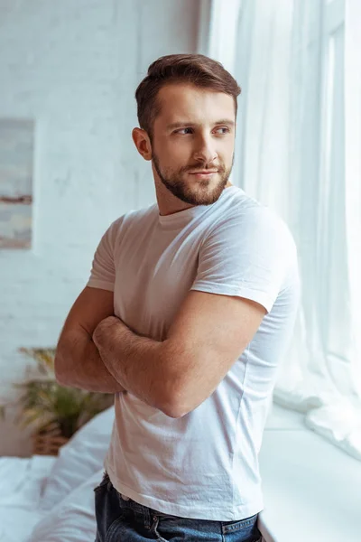 handsome man with crossed arms in white t-shirt looking away