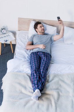 evde yatakta dinlenirken akıllı telefon ile selfie alarak yakışıklı adam