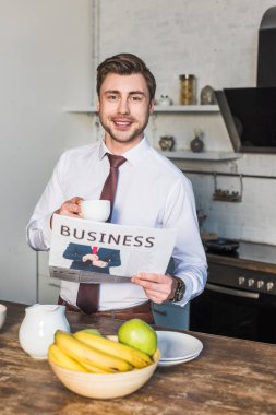 Kamera bakarken neşeli adam Holding iş gazetesi ve kahve bardağı