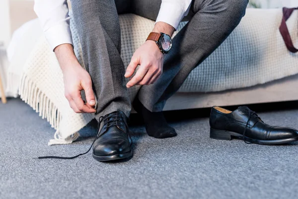Частичный Вид Человека Надевающего Черную Кожаную Обувь Сидящего Постельных Принадлежностях — стоковое фото