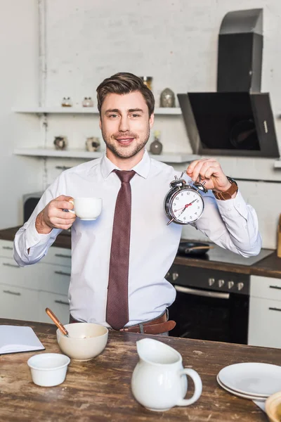 Cheerful Man Holding Coffee Cup Alarm Clock While Standing Kitchen — Stock Photo, Image