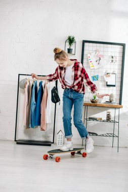 Kot pantolon ve yatak odasında Longboard ayakta damalı gömlek genç tam uzunlukta görünümü