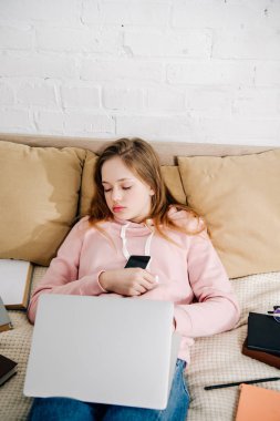 Yatakta uyku laptop ve Kitaplar ile yorgun genç çocuk