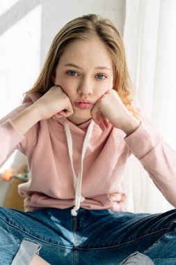 Elleri ile pembe hoodie yaslanır yüz sıkılmış genç çocuğun ön görünümü ve kamera bakıyor