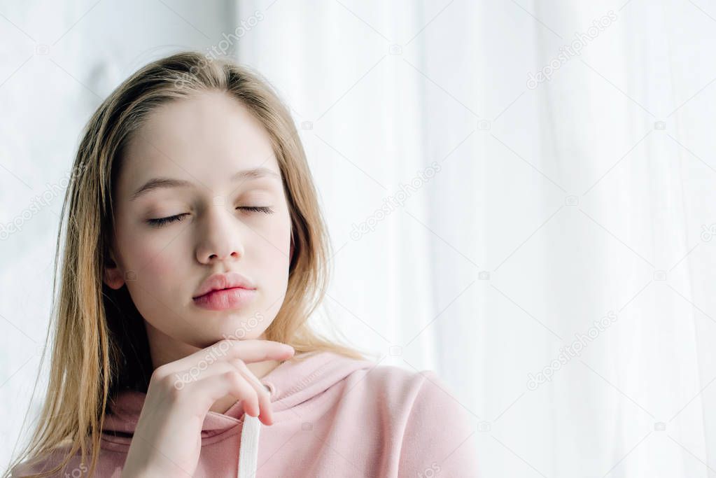 Relaxed teenage kid in pink hoodie with closed eyes