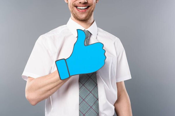обрезанный вид улыбающегося бизнесмена с вырезанным пальцем на сером фоне
