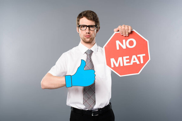 serious businessman in glasses with paper cut thumb up holding red card with no meat lettering on grey background