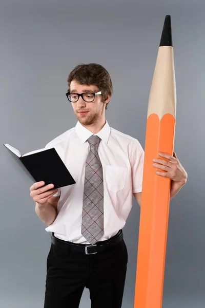 Concentrated Businessman Glasses Holding Huge Decorative Pencil Reading Book Grey — Stock Photo, Image