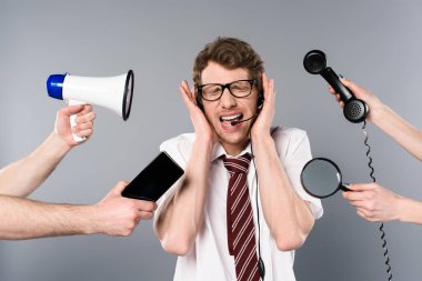 stressed call center operator in headset screaming near megaphone, smartphone, magnifier and telephone  clipart