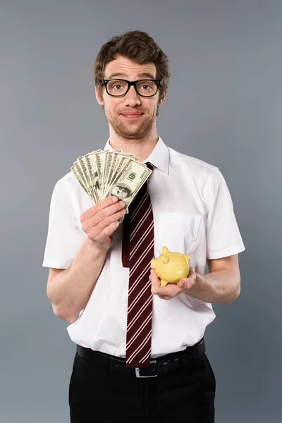 Homem Negócios Óculos Segurando Banco Porquinho Notas Dólar Fundo Cinza — Fotografia de Stock