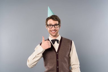 smiling man in party cap and glasses showing thumb up clipart
