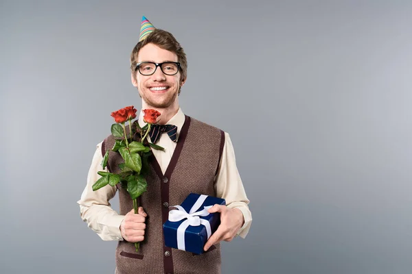 バラの花束とギフト ボックスを保持パーティー キャップで笑みを浮かべて男 — ストック写真