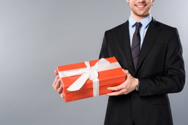gri arka plan üzerinde mevcut tutan gülümseyen iş adamı görünümünü kırpılmış