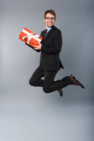 Happy Businessman Holding Present While Jumping Grey Background — Stock Photo, Image