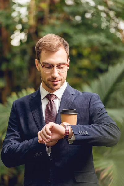 Smiling Businessman Suit Tie Glasses Holding Coffee Looking Wristwatch Greenhouse — Stock Photo, Image