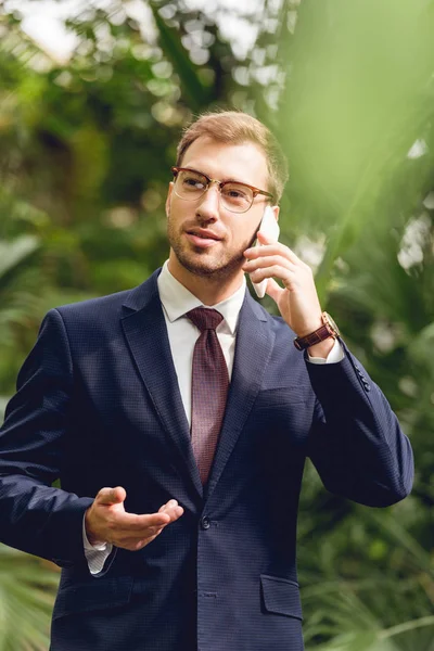 Przystojny Biznesmen Garniturze Krawat Okulary Rozmawiają Smartfonie Szklarni — Zdjęcie stockowe