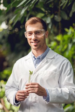 turunculuk bitki örneği ile şişe tutan beyaz ceket ve gözlük mutlu bilim adamı
