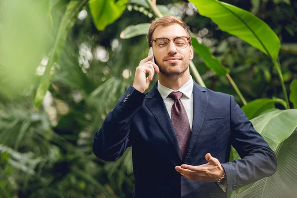スーツ ネクタイ メガネを着たハンサムなビジネスマンは スマートフォンで話し 温室で新鮮な空気を吸い込む目を閉じた — ストック写真