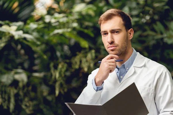 Pensive Scientist White Coat Holding Journal Green Orangery — Stock Photo, Image