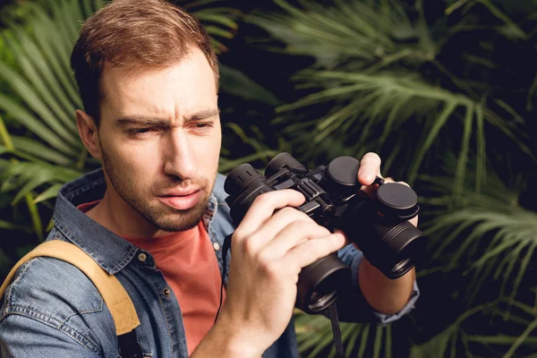 英俊的游客用望远镜在热带森林中望去 — 图库照片