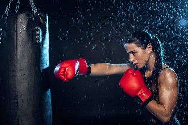 Pensive boxer in red boxing gloves training under water drops on black clipart