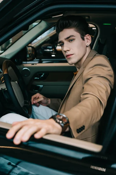 車のショールームで自動車に座っているハンサムな男性の選択的フォーカス — ストック写真