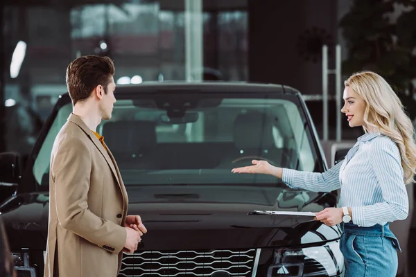 Negociante Carro Loira Alegre Mostrando Automóvel Para Homem Bonito Showroom — Fotografia de Stock