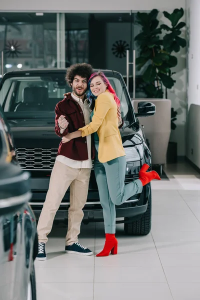Happy Girl Colored Hair Hugging Cheerful Curly Man Car Showroom — Stock Photo, Image