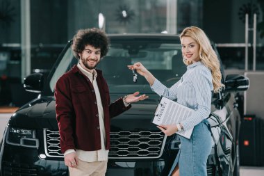 Araba showroom mutlu kıvırcık adam anahtar veren neşeli sarışın araba Bayi 