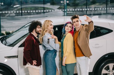 arkadaşlar mutlu grup beyaz araba yakın akıllı telefonda selfie alıyor 