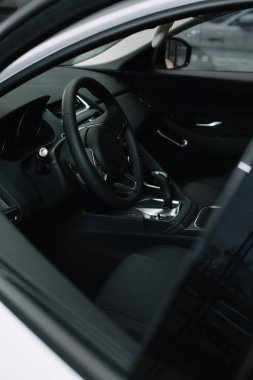 selective focus of black steering wheel near gear shift handle in luxury car  clipart
